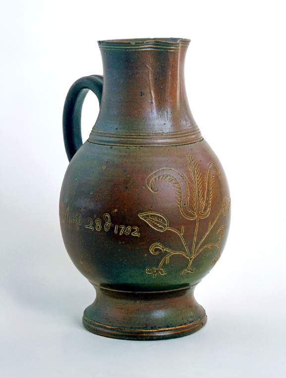 An image of Decanter Jug. Production Place: Nottingham. Brown salt-glazed stoneware, thrown and incised, dated 1702. Provenance: From Firtchley near Crich.