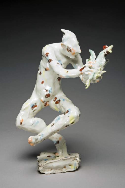 An image of Studio Ceramics. Contemporary Craft. Catching the Cock. Flyn, Michael (British, b. 1947). Figure of a nude man on a small, shallow, triangular base with uneven sides, and of uneven height. He stands on the ball of his right foot. His right leg is bent at the knee, and his left leg, also bent at the knee, is crossed in front of the other leg with the foot in the air. His torso is leaning slightly to the left as he reaches out with both arms to grasp a cockerel which is flying towards the viewer. The man has a long nose, large ears, and hair flying out into two points at the back. His 'cock' is erect (it would probably have dropped off during firing otherwise). Porcelain hand-modelled, glazed and painted with dabs of turquoise-blue, green, yellow, orange, and dark red. Height, whole, 32.8 cm, 1999. Gift of Nicholas and Judith Goodison through the National Art Collections Fund.