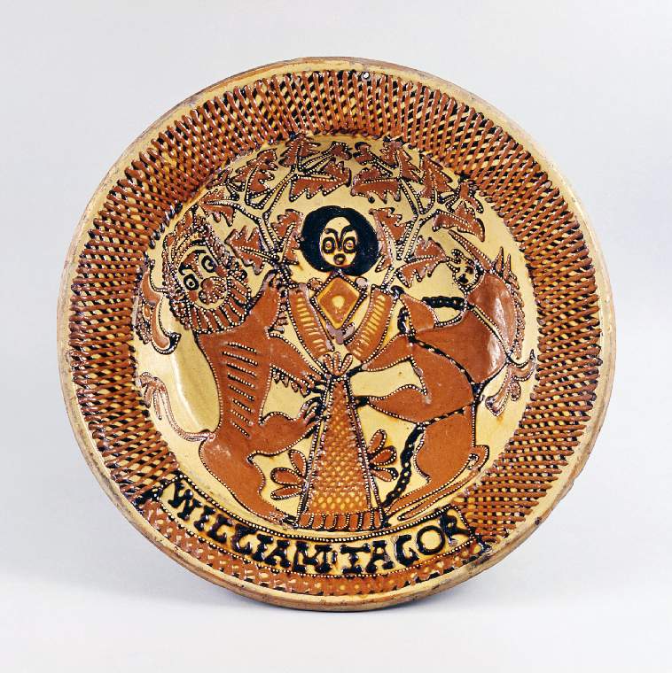 An image of Charger/dish. The Head of Charles II in an Oak Tree. Talor, William (active second half of 17th century, Staffordshire). Charles II's head in the Boscobel Oak flanked by a lion and a unicorn. Circular with a broad slightly sloping rim, concave sides, and flat central area. The well is decorated with the head of Charles II in the Boscobel Oak flanked by a lion rampant and a unicorn. On the rim there is a trellis border with a panel at the bottom containing the name 'WILLIAM TALOR'. Pale red earthenware, thrown, coated in cream slip, slip-trailed in cream, dark red-brown, and pale orange slips, and lead-glazed, the reverse is unglazed. Width, whole, 44 cm, circa 1660-1680.