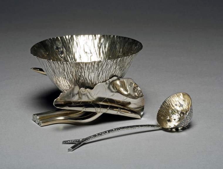 An image of Sugar bowl. Sugar sifter/spoon. Hukin, Jonathan Wilson, silversmith (British). Heath, Thomas, silversmith (British). Dresser, Christopher, designer, perhaps (British, 1834-1904). The bowl is in the form of a lotus flower with a lightly gilt interior, supported by a bent tubular stem, and two curled leaves with engraved veins and tubular stems branching out to right and left from beside the main stem. One leaf is completely curled, the other half open. The sifter spoon has a twig-shaped handle with forked terminal. It's bowl is of the same lotus flower form as the sugar bowl and it also lightly gilt; it is pierced with a pattern of lozenges and roundels. Silver, parcel-gilt, chased and engraved, height, bowl, 8.1 cm, varies, width, bowl, 12.4 cm, weight, bowl, 220 g, length, spoon, 14.9 cm, weight, spoon, 27 g, 1884-1885. Arts and Crafts. Production Note: The attribution of the design to Christopher Dresser is uncertain.