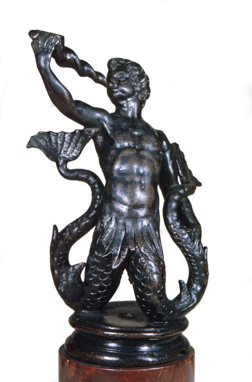 An image of Bifurcate TritonBronze with somewhat rubbed black patina, mounted on a circular moulded bronze base with a screw hole in the centre. The triton is blowing a long conch, which he holds with his right hand, whilst holding his tail with his left hand.  Cylindrical marble plinth.Italian, VeniceC.1560-1630