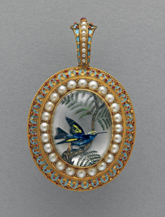 An image of Thomas, William James. Reverse crystal intaglio of a bird on a branch mounted in gold, enamelled in pale blue and red and set with pearls. Oval with a loop for suspension at the top, decorated en suite with the mount. Behind the intaglio there is a compartment for a phototgraph or hair. The back of the mount is engraved with the word 'Vienna' and the date '1873'.