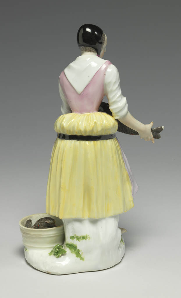 An image of Girl selling carp. Meissen Porcelain Manufactory, Saxony. Hard-paste porcelain, press-moulded, and painted in enamels. The flat underside is unglazed and has a circular ventilation hole near the back. Height, whole, 18.6 cm, width, whole, 11.2 cm, circa 1740-1745. Production Note: The figure was modelled by J.J. Kaendler after 'Carpe Vive' the 6th print in the second series of engravings entitled 'Études prises dans le bas Peuple ou les Cris de Paris' engraved by the comte de Caylus (1692-1765) after drawings by Edmé Bouchardon (1689-1762), which were published in 1737.