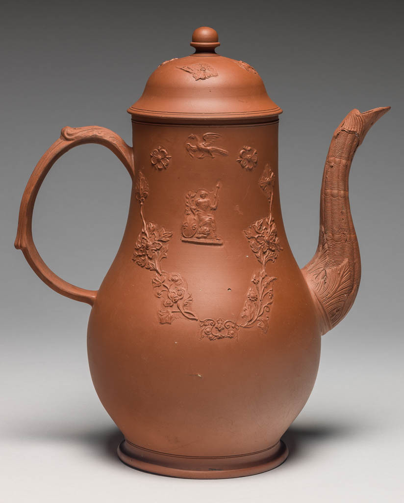 An image of Coffee pot and cover. Unknown Staffordshire factory. The body thrown, with applied moulded handle and spout, and mould applied sprigging. The pot is pear-shaped with a long curved spout moulded with wicker pattern and foliage, and a loop handle. One side is decorated with a mould-applied figure of Britannia with lion and Union Jack shield, on which is the number '45'; on the other side there is a grotesque Chinese figure seated under a parasol. Above both figures there is a flying bird, and below a festoon of mould applied stylized flowers and scrollwork. The domed cover is decorated with a similar bird and flowers, and has an acorn-shaped knob. Red dry-bodied stoneware, circa 1763-1765. Rococo.
