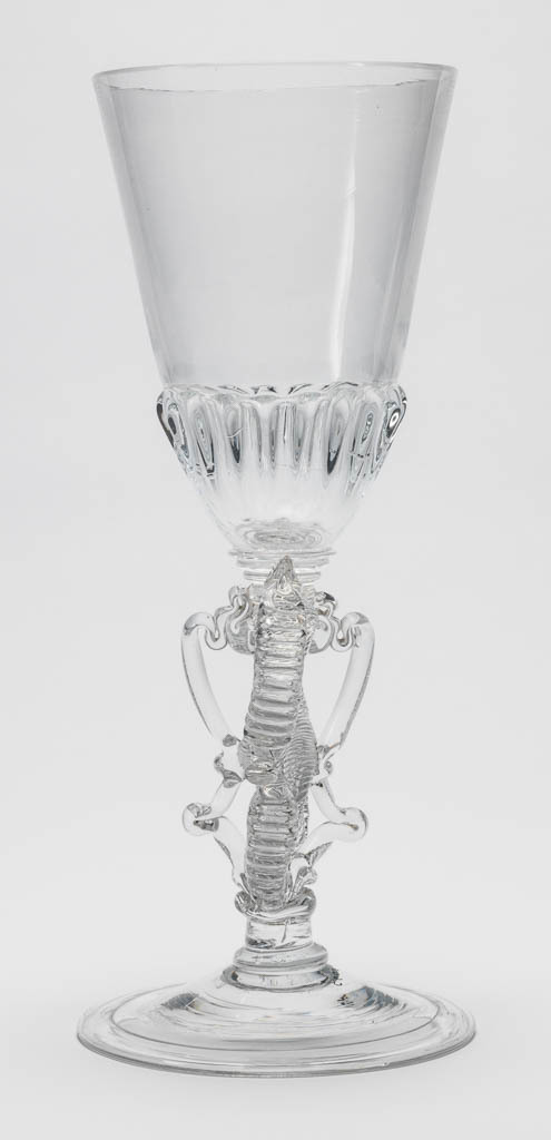 An image of Ceremonial goblet/drinking glasses. Unknown glassmaker. Heavy, moulded gadrooning on base of bowl and on cover; figure-of-eight stem; folded foot; cover finial composed of trailed and dentilated scrolls to either side of a tall spire constructed of a series of knops. Clear lead-glass, bowl blown, height, goblet, 37.5 cm, diameter, goblet, 15.5 cm, height, cover, 14.4 cm, diameter, cover, 15.4 cm, circa 1713.