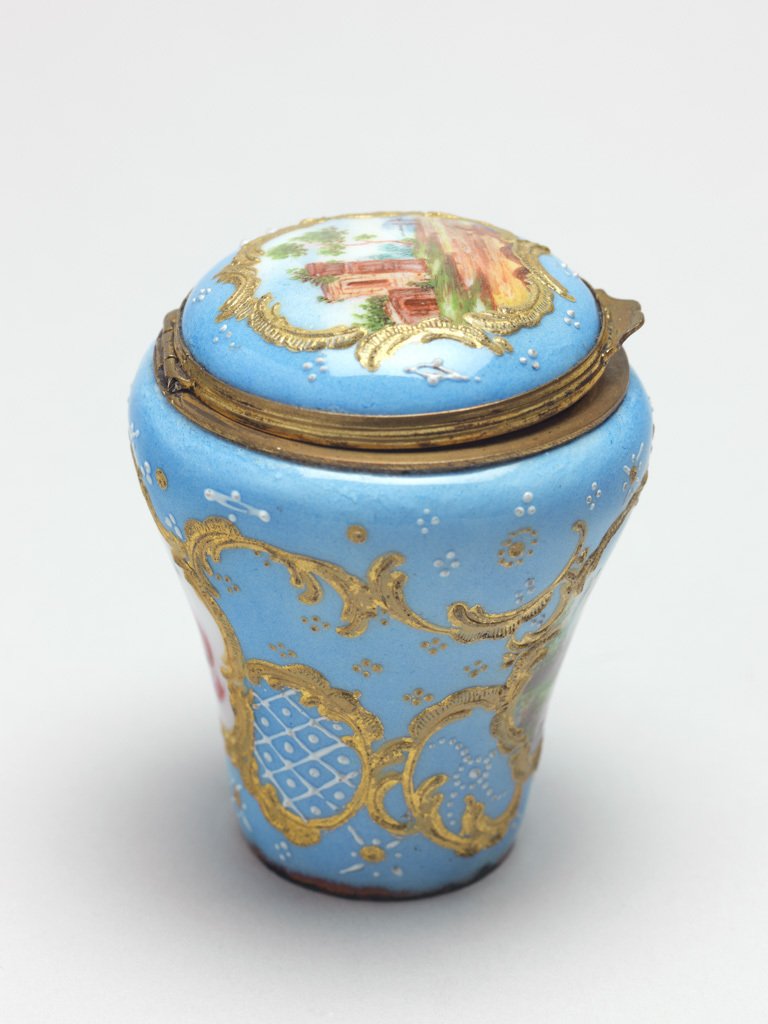 An image of Cane Handle/Snuff Box. Objets de vertu. Unknown maker, Staffordshire. Baluster-shaped handle for a walking cane set with a hemi-spherical gilt metal snuff box with a hinged lid. On two sides and the lid are painted miniatures within rococo raised gilt borders. The pale blue ground decorated with white diaper-work and geometric patterns of gold and white dots. The rim of the lid and box have gilt metal mounts and thumbpiece. The miniature on the lid depicts a Classical ruin in a pastoral scene; the miniature on the front depicts a man and cow in a rural landscape with a church tower and cottage in the background, and the miniature on the back depicts a spray of flowers on a white ground. Copper, enamelled in polychrome, with gilt metal mounts, height, whole, 5.5 cm, diameter, whole, 4.5 cm, circa 1750-1775.
