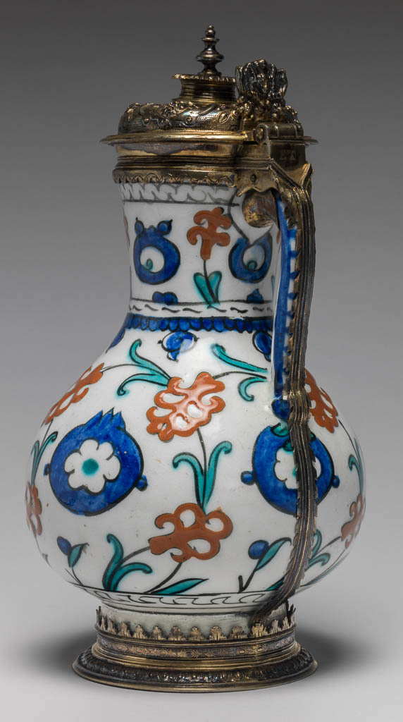 An image of Fritware Jug. Unknown Maker. Painted red slip, blue green and black under a colourless, slightly pitted glaze, silver gilt mounts. Height, whole, 26.2 cm, width, whole, 14.2 cm, diameter, rim, 7.7 cm, diameter, base, 9.8 cm, weight, whole, 780 g. Jug: Ottoman Period, Islamic. Production Place: Turkey. Mounts: Elizabethan, circa 1580-1593. Production Place: London.