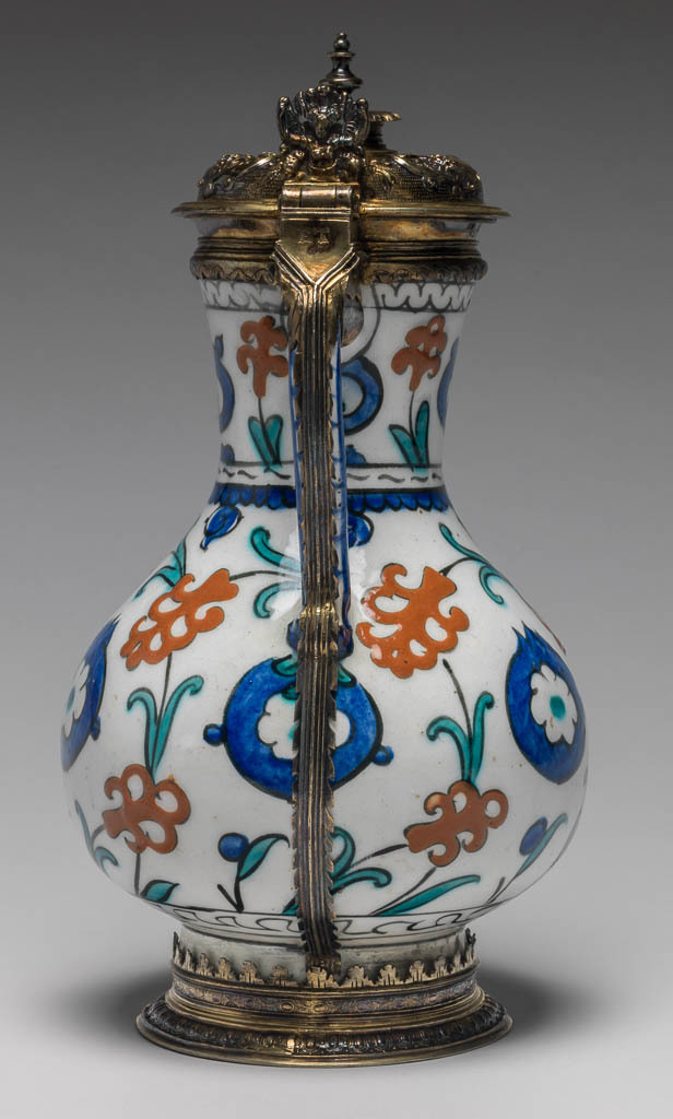 An image of Fritware Jug. Unknown Maker. Painted red slip, blue green and black under a colourless, slightly pitted glaze, silver gilt mounts. Height, whole, 26.2 cm, width, whole, 14.2 cm, diameter, rim, 7.7 cm, diameter, base, 9.8 cm, weight, whole, 780 g. Jug: Ottoman Period, Islamic. Production Place: Turkey. Mounts: Elizabethan, circa 1580-1593. Production Place: London.