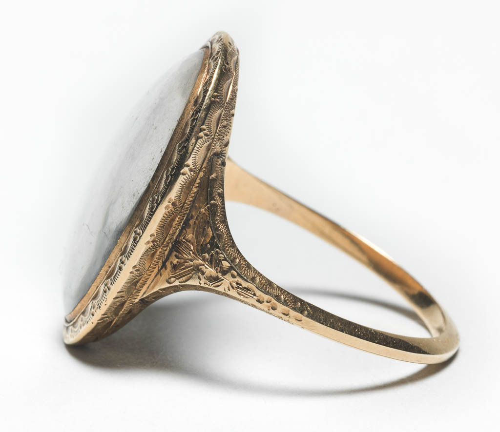 An image of Jewellery/Mourning Ring. Inscribed, 'Elizabeth Dixon died aged 62, 13 Jan 1780'. Plain gold hoop widening at shoulders. Shoulders decorated with chased foliate design. Long oval bezel with chased border surrounding, under glass, a wheatsheaf of hair bound with pearls, on ivory. Height, hoop, 2.0 mm, length, hoop, 23.0 mm, height, bezel (oval) 5.0 mm, width, bezel (oval) 17.0 mm, length, bezel (oval) 24.5 mm, 1797.