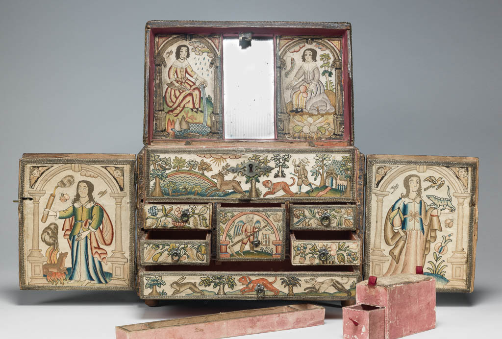 An image of Textiles. Casket with embroidered panels. Outside covered with linen, polychrome silk embroidery in rococo, tent, back, and couching stitches. Depicting the five senses: on the top Smell, on the doors Hearing and Sight, on the sides Touch and Taste. On the back Orpheus with his lyre.   Inside covered with white silk, polychrome silk embroidery in satin, dot and couching stitches with some silk covered wire. Depicting the elements: on the doors Fire and Air, on the lid Water and Earth. Further pastoral and hunting pictorial scenes inside front, Time with hour glass and scythe in centre of drawers. Silk, polychrome silk embroidery on a wooden base with mirror in lid. Height 23.6 cm, width 27.1 cm, depth 16.5 cm, circa 1650-1674. English.