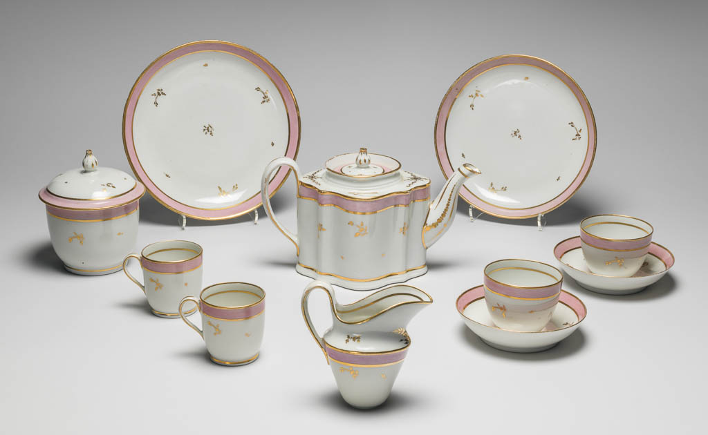 An image of Tea Service/Tea Set. New Hall Porcelain Factory, Staffordshire. Comprising a teapot and cover of 'silver' shape, a milk jug, sugar basin and cover, a slop basin, two plates of different sizes, two tea bowls, two coffee cups and two saucers. Each piece is decorated with a wide band of pink enamel between narrow gold bands and with scattered floral sprigs in gold. In addition, the milk jug has two sprays of leaves below the lip, and the teapot has sprays of leaves and formal ornament on the shoulder and further formal ornament on spout and handle. Pattern no. 223. Hybrid hard-paste porcelain, moulded, and painted lead overglaze, decorated with pink enamel and gilt, height, teapot, 14.4 cm, length, teapot, 24.1 cm, height, sugar basin, 13.5 cm, diameter, sugar basin, 10.3 cm, height, slop basin, 7.4 cm, diameter, slop basin, 15.2 cm, height, milk jug, 11.5, cm, height, plate, 3.2 cm, diameter, plate, 23.8 cm, height, plate, 3.1 cm, diameter, plate, 20.1 cm, height, coffee can, 6.6 cm, height, tea bowl, 6.1, cm, diameter, tea bowl, 7.6, cm, height, saucer, 3.2, cm, diameter, saucer, 13.1, cm, circa 1785. Rococo.