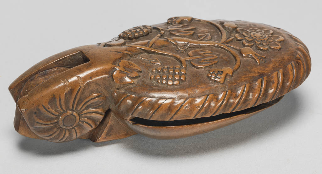 An image of Cutlery/Spoon/Flatware. Folding, in the form of two hinged oval bowls. The back of the one used as a handle is carved with a tree with stylised flowers and fruit within a gadroon border; the inside is deeply carved as a woman on horseback. The wood was carved in two pieces which were joined with a hinge. Fruit wood, length, overall, 14.5 cm, circa 1650-circa 1700. German.