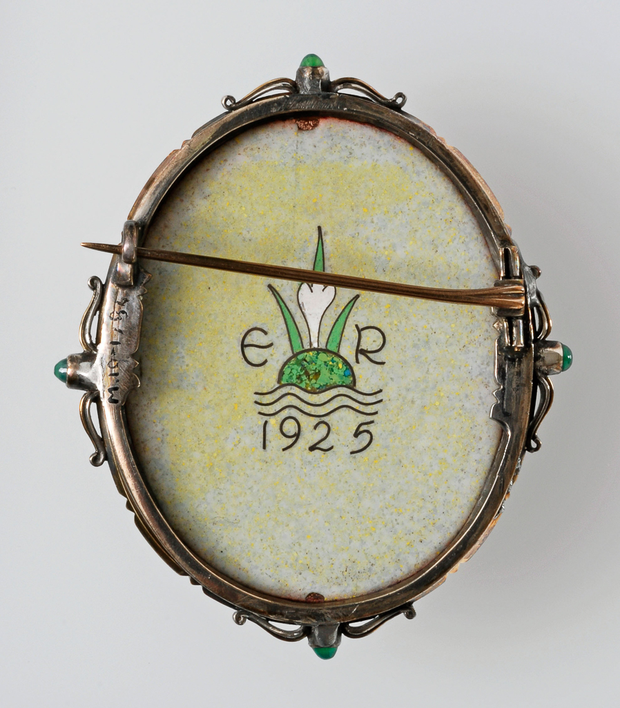 An image of Jewellery/Brooch. Unknown maker. On the front, a cloisonné enamel design of a girl in a 'Greek' tunic carrying a basket of flowers over her head; on the back, a cloisonné enamel crocus, flanked by the initials 'E R' over waves and the date '1925' in gold. Oval enamelled copper plaque set in a silver and gold frame decorated with four cabochon green gemstones; pin fastening across the back. Height, whole, 6.8 cm, width, whole, 5.8 cm, dated 1925. English. Acquisition Credit: Given by Mrs J. Hull Grundy.
