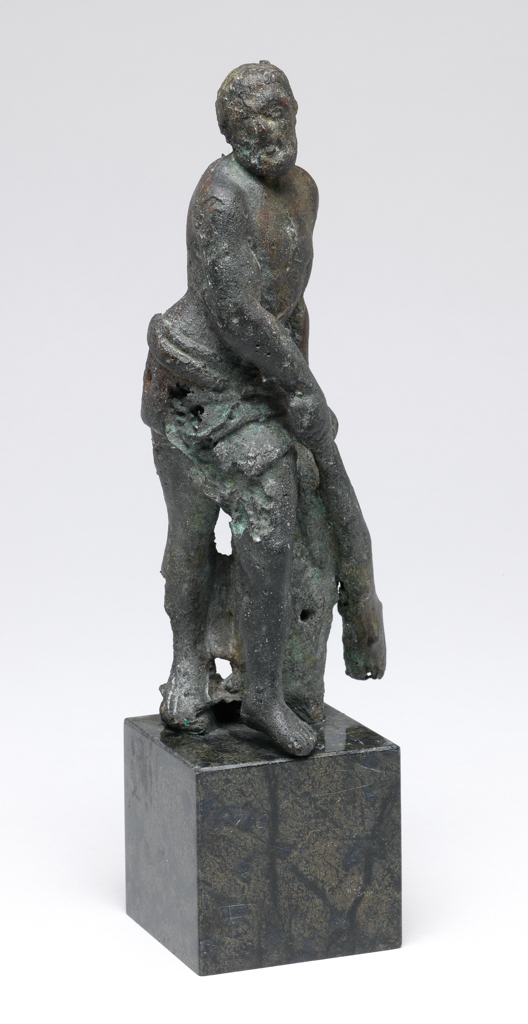 An image of Sculpture/figure. Hercules. Unknown maker, Florence. Hercules stands on his right leg with his left leg advanced. His right arm is held across his body, the hand grasping a club. His left hand rests on the top of a tree stump. There is a drape around his hips. Bronze, cast, standing on a green and black marble base, height, whole, 16.1 cm, circa 1670-1700. Production Note: Bronze, a casting disaster. It is of interest due to this fact.