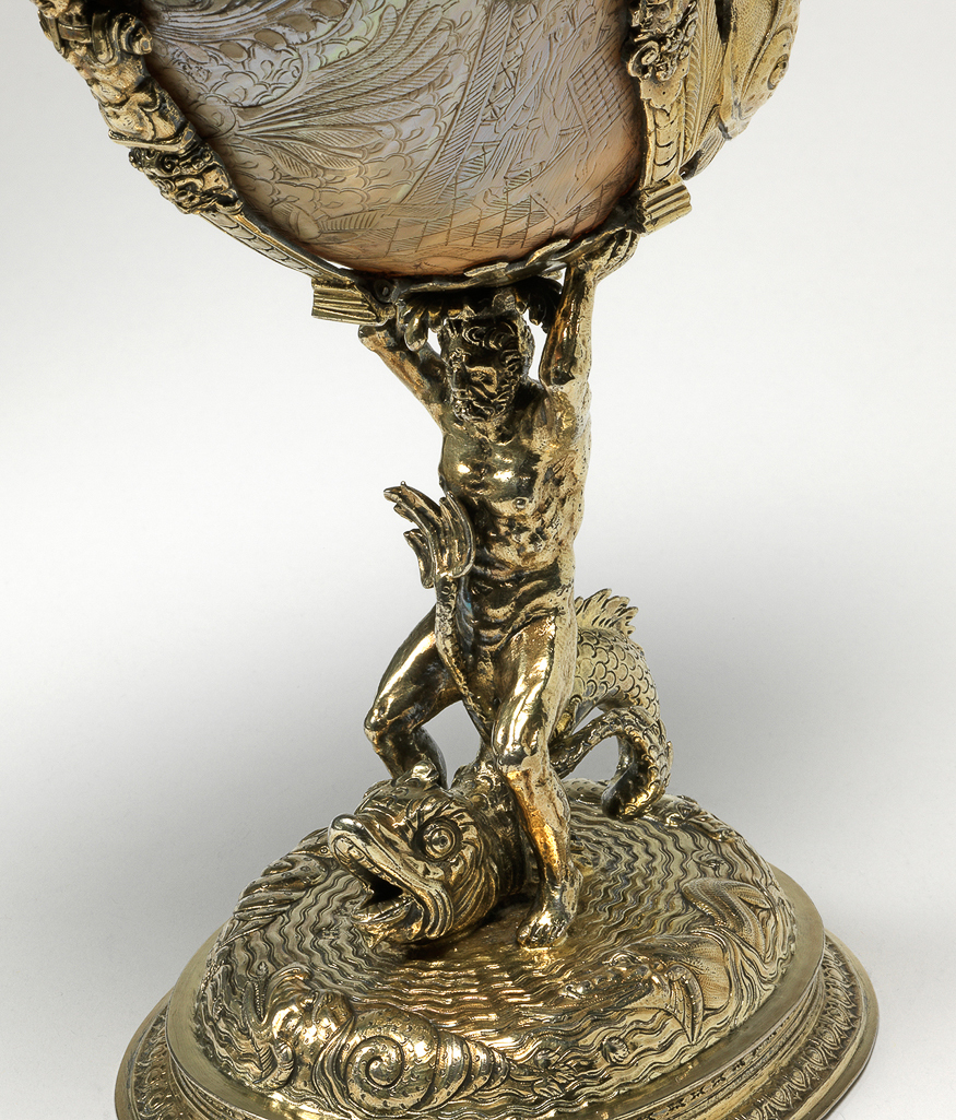An image of Nautilus shell cup engraved with Chinese scenes and mounted with silver-gilt aquatic emblems. Nautilus shell with engraved decoration, mounted in silver-gilt, cast, embossed, chased and engraved, height (overall) 24.4 cm, width (overall) 10.8 cm, length (overall) 19 cm, c.1585-1586. London silversmith. Mannerist.