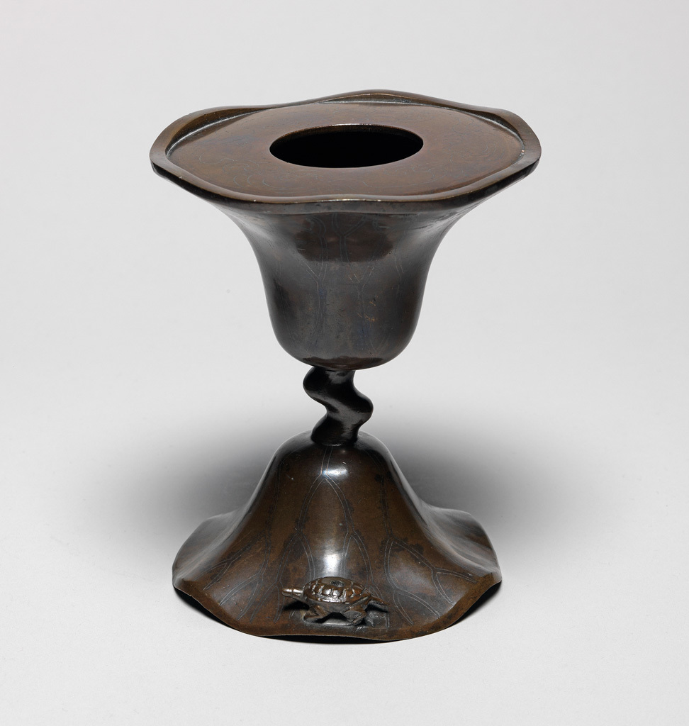 An image of Bronze candlestick, inlaid with silver, in the shape of a lotus leaf with a wavy edge. possibly Korean. 1600-1799.