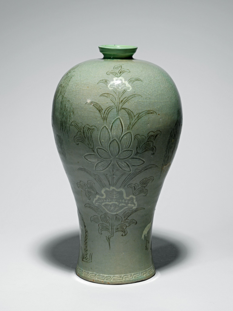 An image of Maebyong. Unknown, probably North Cholla province, Puan-gun, Yuch'on-ri kilns. Vase with willow trees, cranes and lotus design. This maebyong-shaped vase has a wide shoulder and a narrow base and rests on a broad low footring. The neck has been restored. The body is inlaid in black and white slip with two large lotus sprays with fully opened blooms, between painterly scenes of cranes under a willow tree. Around the base is a band of key-fret in white slip. The glaze is of opaque pale bluish-green tone, glossy, and with a fine crackle. The glaze has been wiped from the footring, which shows traces of ten fire-clay spurs. Stoneware, thrown, inlaid in black and white slip, and celadon-glazed, height, whole, 34.6 cm, diameter, rim, 5.7 cm, diameter, foot, 12.2 cm, circa 1200-1250. Koryo Dynasty. Production Note: This type of maebyong was used as a container for fine wine, made from plum flowers or ginseng. It originally probably had a cover.