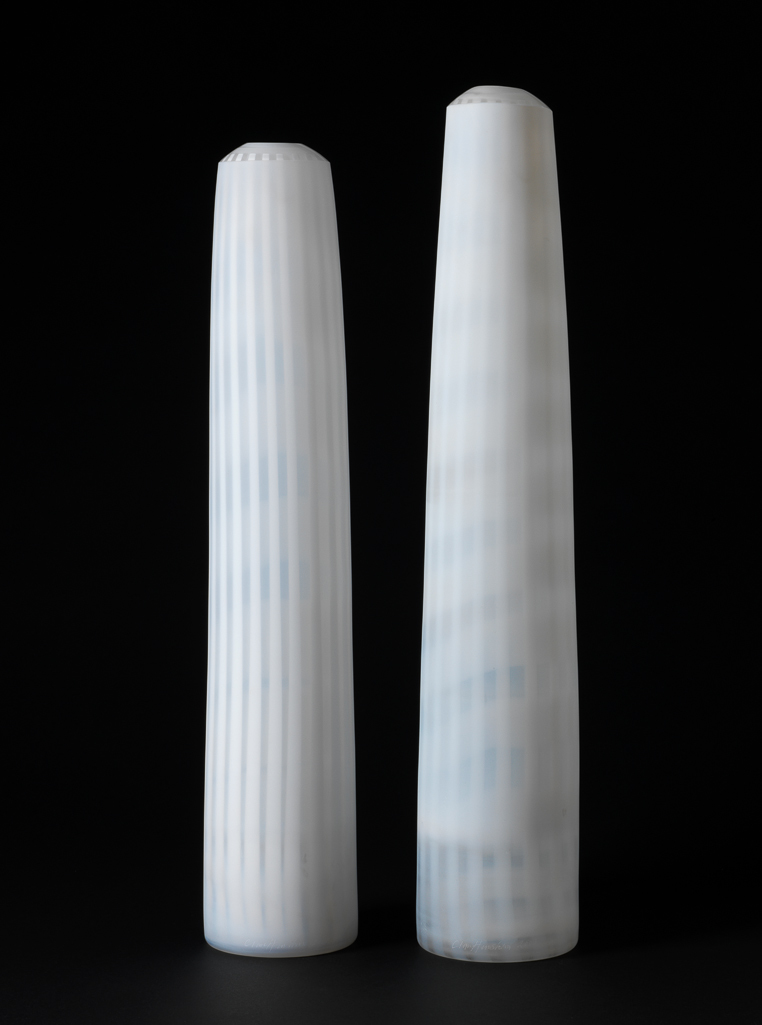 An image of Studio Glass. Two Tall Forms. Henshaw, Clare (British, b.1964). Two tall cylindrical forms of uneven height, of blown and layered clear and white glass formed by the Swedish 'graal' technique to produce vertical white stripes within the glass. Blown and layered clear and white glass formed by the Swedish 'graal' technique to produce vertical white stripes within the form. Height, A, 56.4 cm, diameter, A base, 10.5 cm, diameter, A top, 6.5 cm, diameter, A aperture at top, 3.3 cm, height, B, 53 cm, diameter, B base, 10 cm, diameter, B top, 7 cm, diameter, B aperture at top, 3.4 cm, 2005. Gift of Nicholas and Judith Goodison through the National Art Collections Fund.