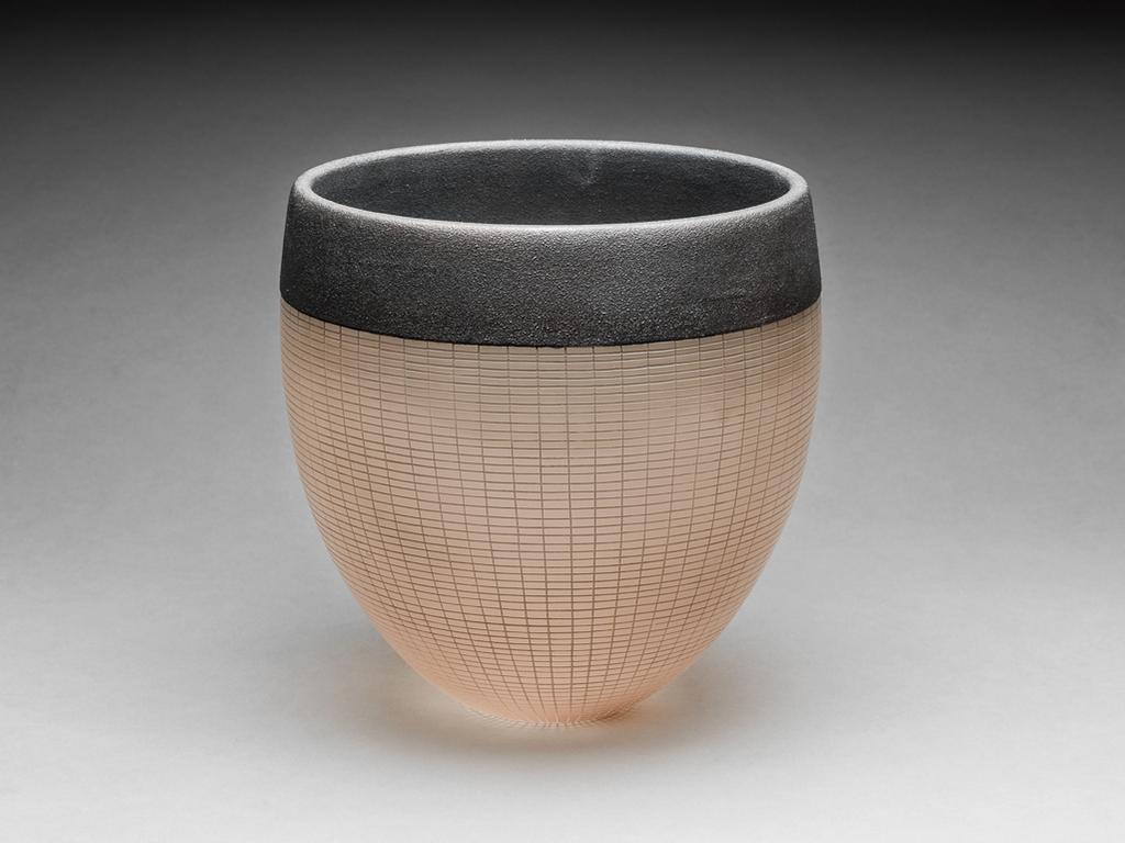 An image of Studio Glass. Light brown glass bowl with sandy rim. Dickinson, Anna Maria (British, b.1961). Light brown clear glass, engraved, etched, and polished, the rim electroformed over sand. Circular with deep sides, curving inwards towards narrow base, which is flat and polished. The exterior is decorated overall with an engraved, graduated rectangular grid pattern. The dark coppery-brown electroformed rim has a sandy surface, and is about 4 cm deep. The interior is etched to produce a matt surface overall. Stuck onto the base there are five small circles of green felt, circa 1999. Gift of Nicholas and Judith Goodison through the National Art Collections Fund.