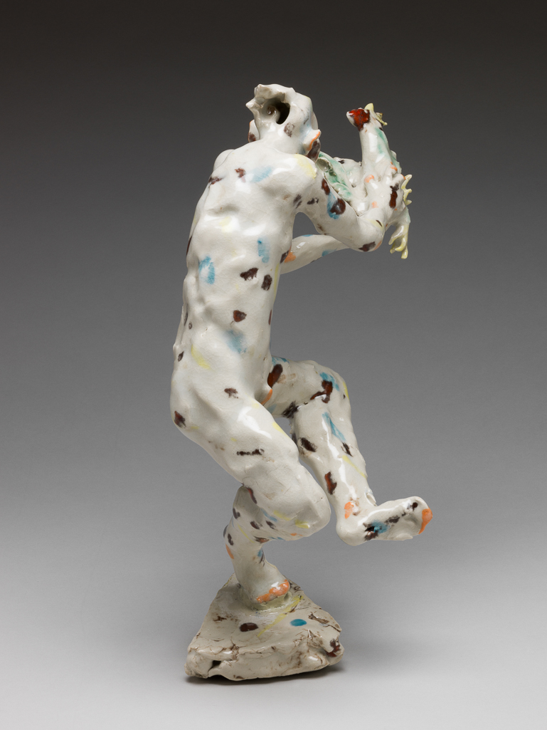 An image of Studio Ceramics. Contemporary Craft. Catching the Cock. Flyn, Michael (British, b. 1947). Figure of a nude man on a small, shallow, triangular base with uneven sides, and of uneven height. He stands on the ball of his right foot. His right leg is bent at the knee, and his left leg, also bent at the knee, is crossed in front of the other leg with the foot in the air. His torso is leaning slightly to the left as he reaches out with both arms to grasp a cockerel which is flying towards the viewer. The man has a long nose, large ears, and hair flying out into two points at the back. His 'cock' is erect (it would probably have dropped off during firing otherwise). Porcelain hand-modelled, glazed and painted with dabs of turquoise-blue, green, yellow, orange, and dark red. Height, whole, 32.8 cm, 1999. Gift of Nicholas and Judith Goodison through the National Art Collections Fund.