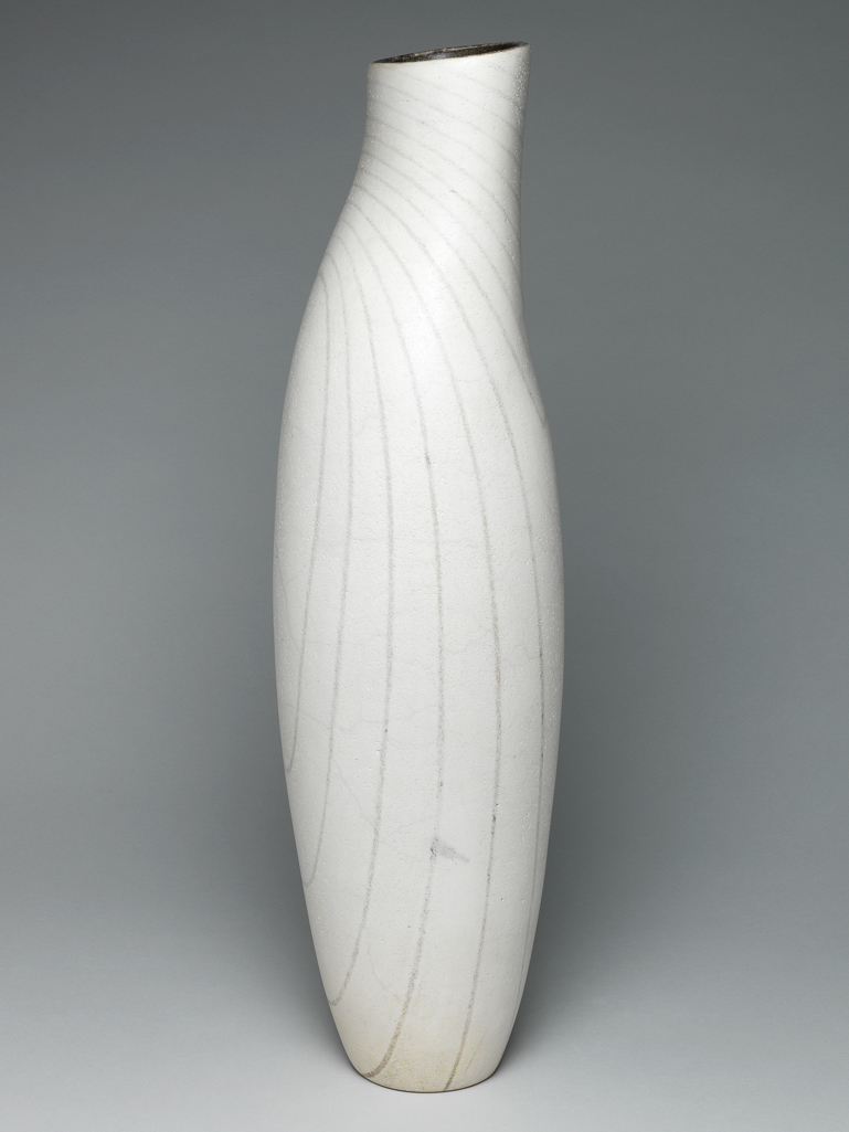 An image of Contemporary Craft. Studio Ceramics. Hand Built Vase Form 1995. Roberts, David (British, b.1947). The tall slender vase stands on a crcular base. The sides swell outwards slightly, and then curve inwards into an elongated, elliptical neck. The mouth is lower at the front than at the back. The grey contour lines are approximately oval on the front, and extend over the whole height. On the back they are angular and stop about a third of the way down from the top. Stoneware (white St Thomas's clay), coiled, with greyish-black glaze inside, and white, crazed glaze outside, decorated with grey contour lines, and raku fired, whole, 55.7 cm, 1995. Gift of Nicholas and Judith Goodison through the National Art Collections Fund.