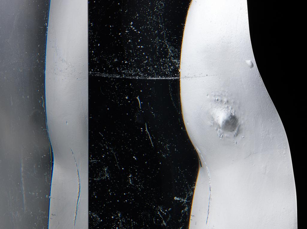 An image of Studio Glass. Aura VII Torso. Romanelli, Bruno (British, b.1968). A narrow rectangular pillar indented with the outline of a human torso with a nipple. The surface of the indentation is sandblasted. Within the glass there are various indeterminate misty markings. Clear glass, cast, sandblasted, and polished, height 41.5 cm, width, top, 14.5 cm, width, bottom, 13.1 cm, depth 9.9 cm, 1999. Gift of Nicholas and Judith Goodison through the National Art Collections Fund.