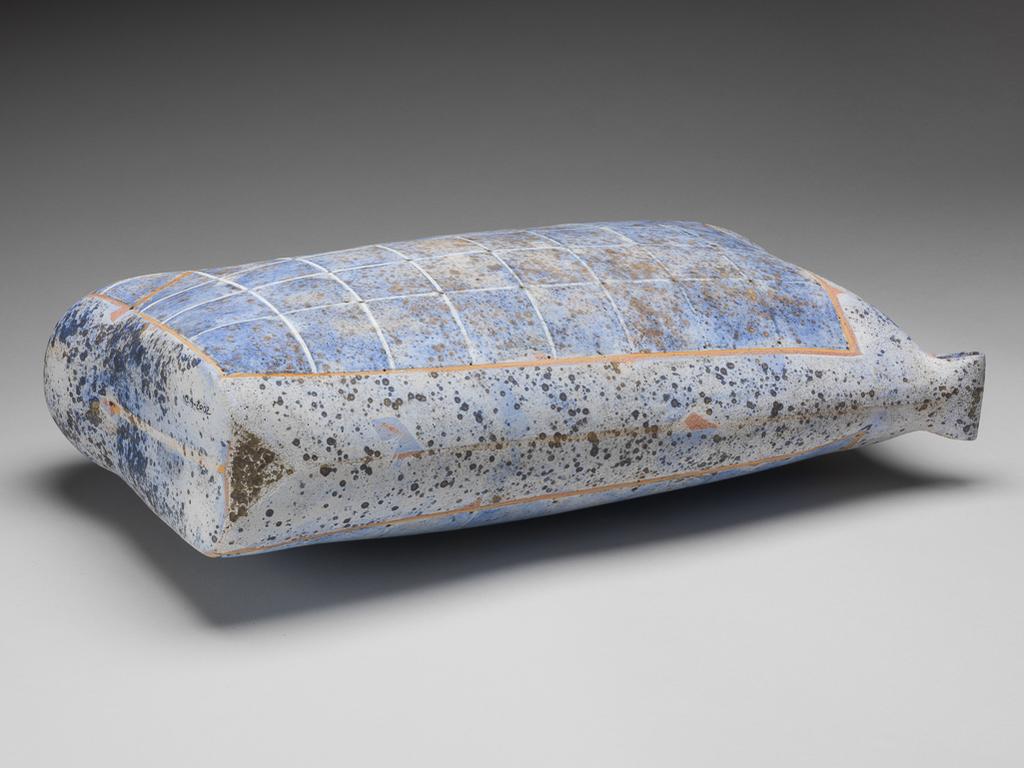 An image of Studio Ceramics. Keeping a Secret. Heinz, Regina (b. Austria 1957). Sack-shaped ceramic form in stoneware, painted with glaze, dappled and chequered in pale brownish-orange, and blue, grey, and black. Of irregular sack shape, more rounded at the lower right corner, angular at top right, and having a folded strap on the top left corner (or vice versa if looked at from the other side). The sides are coated overall with a greyish-white glaze with greyish-black and black speckles, and decorated with a rectangle outlined in pale orange-brown, chequered with white lines with pin holes at the intersections, and dappled in blue. Across the rounded lower corner there is a diagonal line of pale orange-brown. Stoneware, hand-built, pierced, and decorated with lithium glaze, producing a speckled effect, slips, and oxides in pale brownish-orange, and shades of blue. Height, whole, 47.8 cm, width, top, 29.5 cm, width, bottom, 26.5 cm, depth, widest part, 14.4 cm, 2001. Given by Sir Nicholas and Lady Goodison through the National Art Collections Fund.