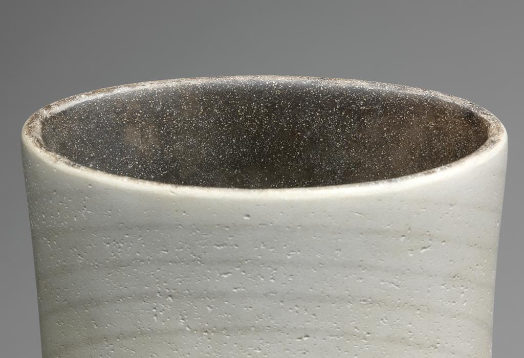 An image of Contemporary Craft. Studio Ceramics. Hand Built Vase Form 1995. Roberts, David (British, b.1947). The tall slender vase stands on a crcular base. The sides swell outwards slightly, and then curve inwards into an elongated, elliptical neck. The mouth is lower at the front than at the back. The grey contour lines are approximately oval on the front, and extend over the whole height. On the back they are angular and stop about a third of the way down from the top. Stoneware (white St Thomas's clay), coiled, with greyish-black glaze inside, and white, crazed glaze outside, decorated with grey contour lines, and raku fired, whole, 55.7 cm, 1995. Gift of Nicholas and Judith Goodison through the National Art Collections Fund.