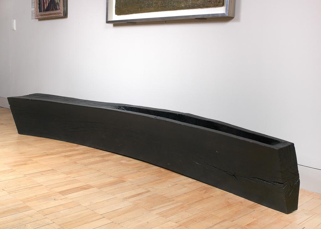 An image of Curved Bench with Trough. Partridge, Jim (British, b. 1953). Walmsley, Liz (British, b.1952). Production Place: Shropshire, Oswestry. Curved and tapering block of wood with a tapering trough in the top of the narrowest part. Oak, carved, and blackened, height, at highest, 39.5 cm, length, whole, 294 cm, length, whole, 272 cm, width, at widest, 43 cm, circa 2004. Gift of Nicholas and Judith Goodison through the National Art Collections Fund.