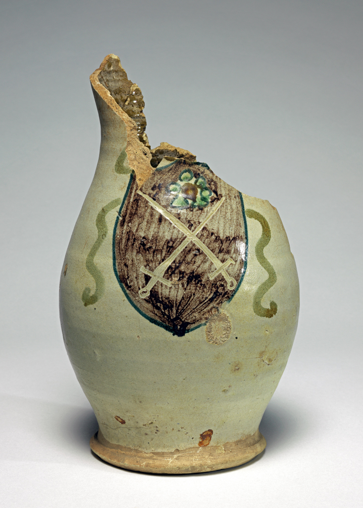An image of Maiolica Jug. Unknown (pottery). Earthenware, the interior lead-glazed olive-green, the exterior tin-glazed pale beige, height 21.8cm, diameter (base) 9.7cm, diameter (widest part) 13.0cm, circa 1375-1450. Umbria, Italy.