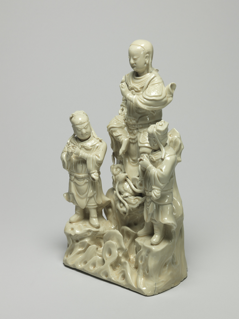 An image of Zhenwa group. Seated Zhenwa with standing military acolytes, a tortoise and snake below on complicated rockwork base. Blanc de Chine. 1575-1599. Chinese.