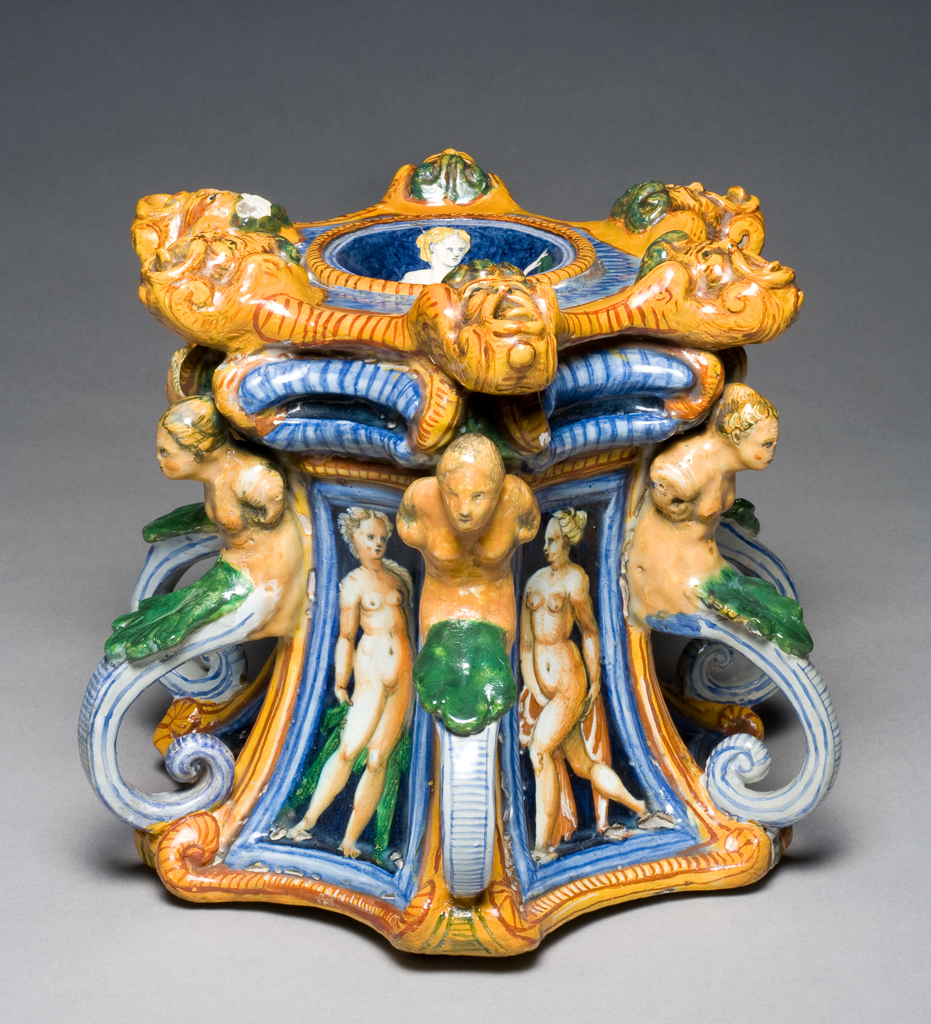An image of Maiolica salt. Painted in polychrome with a nymph, masks, herms and female nudes. Production Place: Urbino, The Marches. Tin-glazed earthenware, height 20.0 cm, width 22.4 cm, length 27.2 cm, circa 1550-1560. Renaissance.