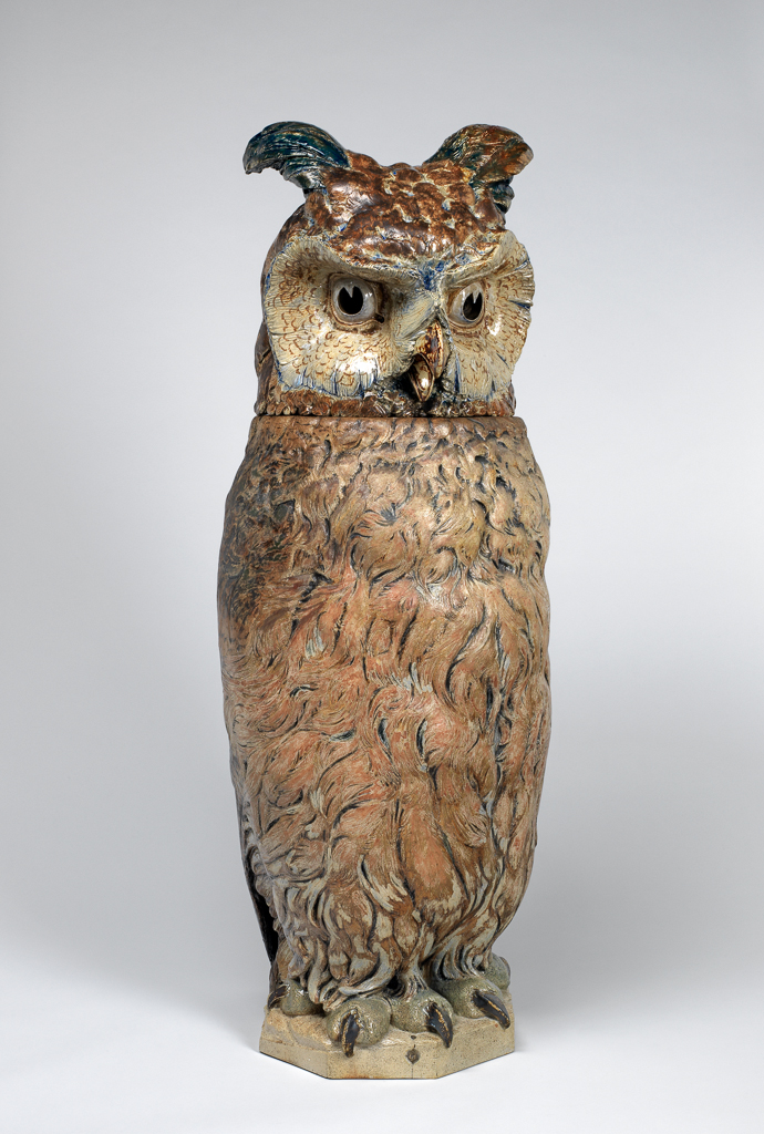 An image of Owl. Martin Brothers, Southall. Martin, Robert Wallace (British, 1843-1923). Stoneware jar and lid, modelled in the shape of an owl, painted with cream, grey and brown coloured slips, and salt-glazed, height, whole, 103cm, diameter, whole, 35.5cm, height, head, 38.5cm, 1903.