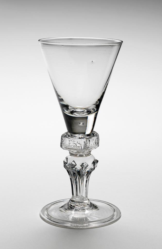 An image of Wine glass. Funnel bowl on square knop moulded 'GOD SAVE KING GEORGE' on moulded pedestal stem and folded foot. Lead glass, bowl blown, stem moulded with engraved decoration, height 16.0cm, diameter (whole) 7.5cm, circa 1715.