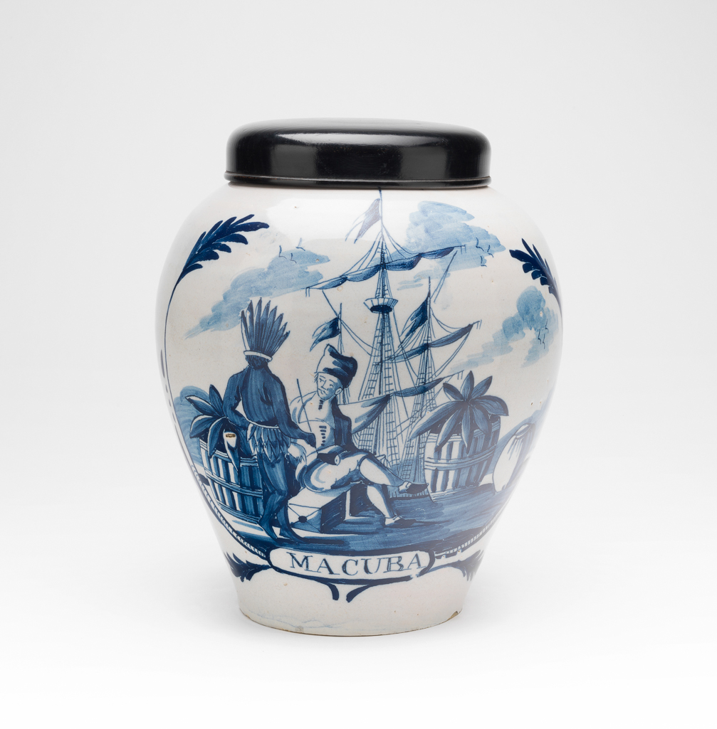 An image of Tobacco Jar painted in blue with a quay scene and labelled 'MACUBA'. The Three Bells Factory, United Provinces of the Netherlands, Delft. Buff earthenware, thrown, tin-glazed, and painted in blue. Height, whole, 25 cm, diameter, whole, 21.6 cm, diameter, cover, 13.3 cm, circa 1750 to 1820.