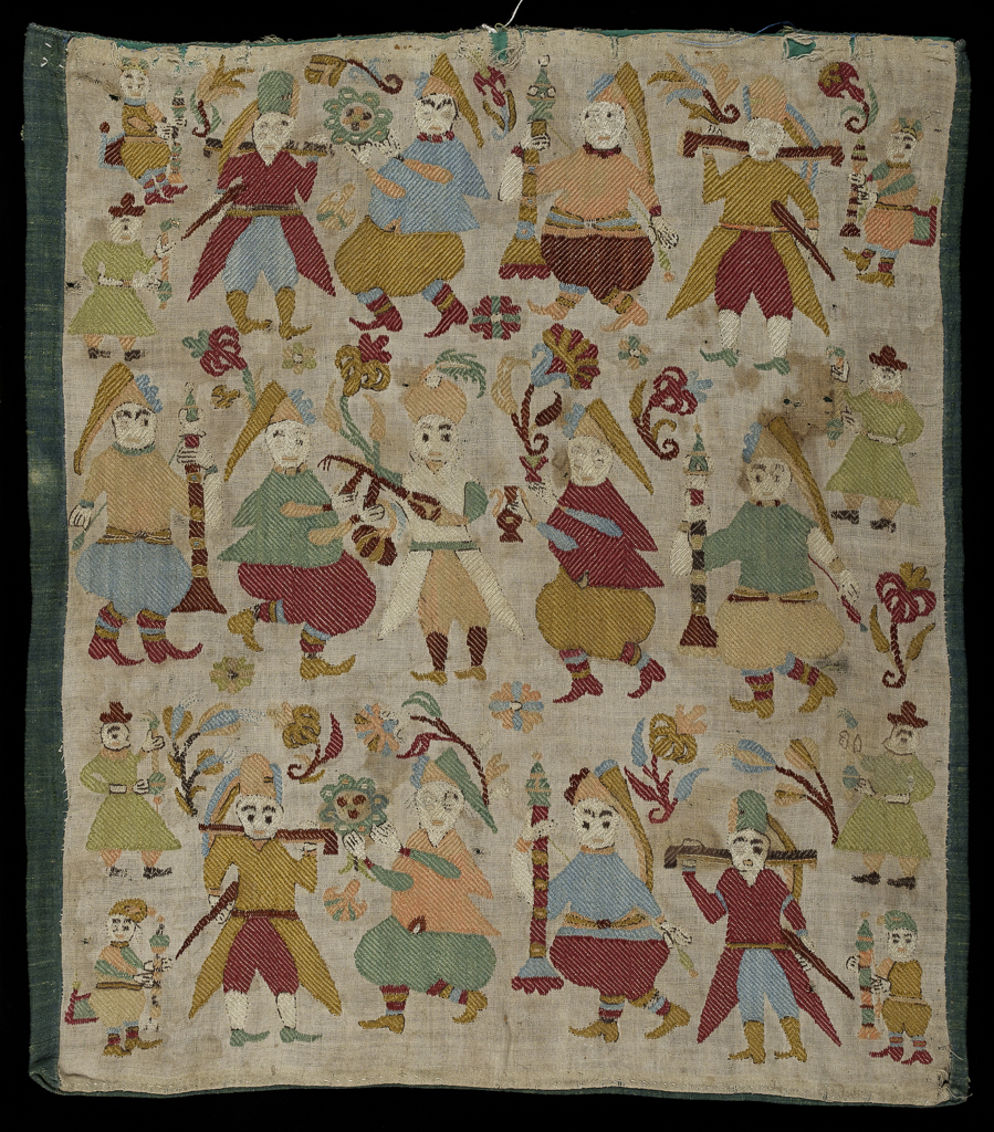 An image of Embroidery / Cushion Cover. Unknown Maker. Linen cushion cover embroidered with polychrome silks in darning, back and satin stitch. The male figures, whether part of the three dominant rows or as smaller scale motifs at each end, carry large candles, flowers, ewers, muskets or swords and possibly a mandolin. There are two distinct dress styles, long coat and breeches or short coat and baggy breeches; heads are variously covered with long caps, turbans or hats. Length 43.5 cm, width 36.5 cm, circa 1701-1801. Skyros, Northern Sporades, Greece.