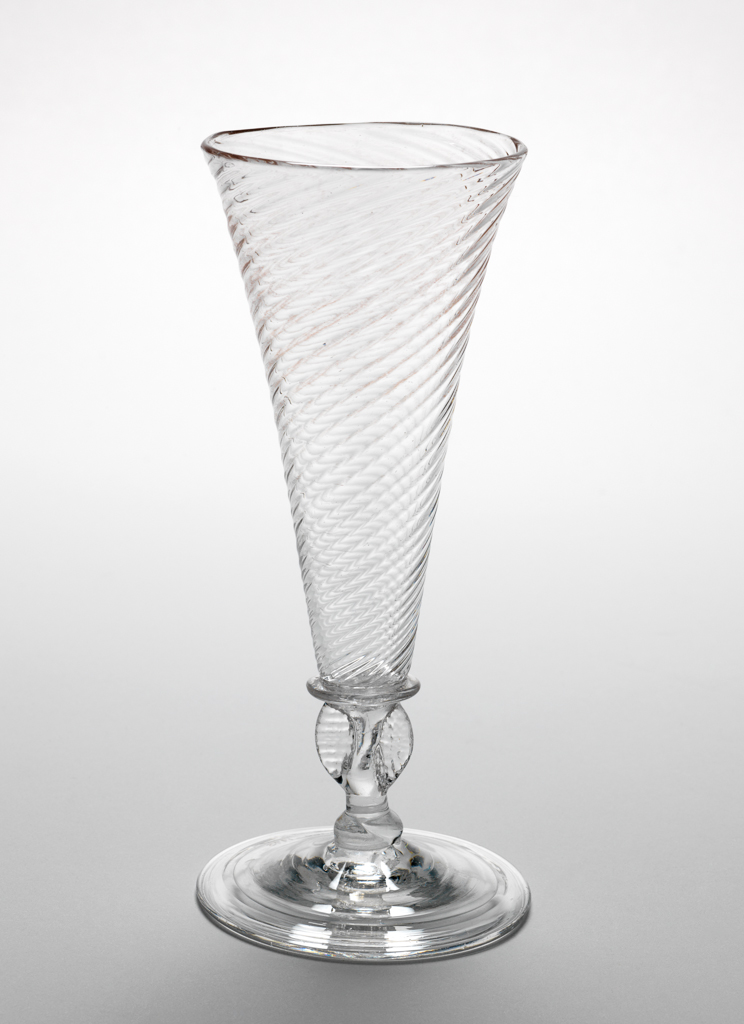 An image of Wine glass/drinking glasses. Unknown English glassmaker. Wrythen funnel shaped bowl, winged stem with knop, folded foot. Uncoloured glass, probably decolourised by addition of manganese. Lead-glass, bowl blown, height, whole, 17.6 cm, circa 1700-1730.