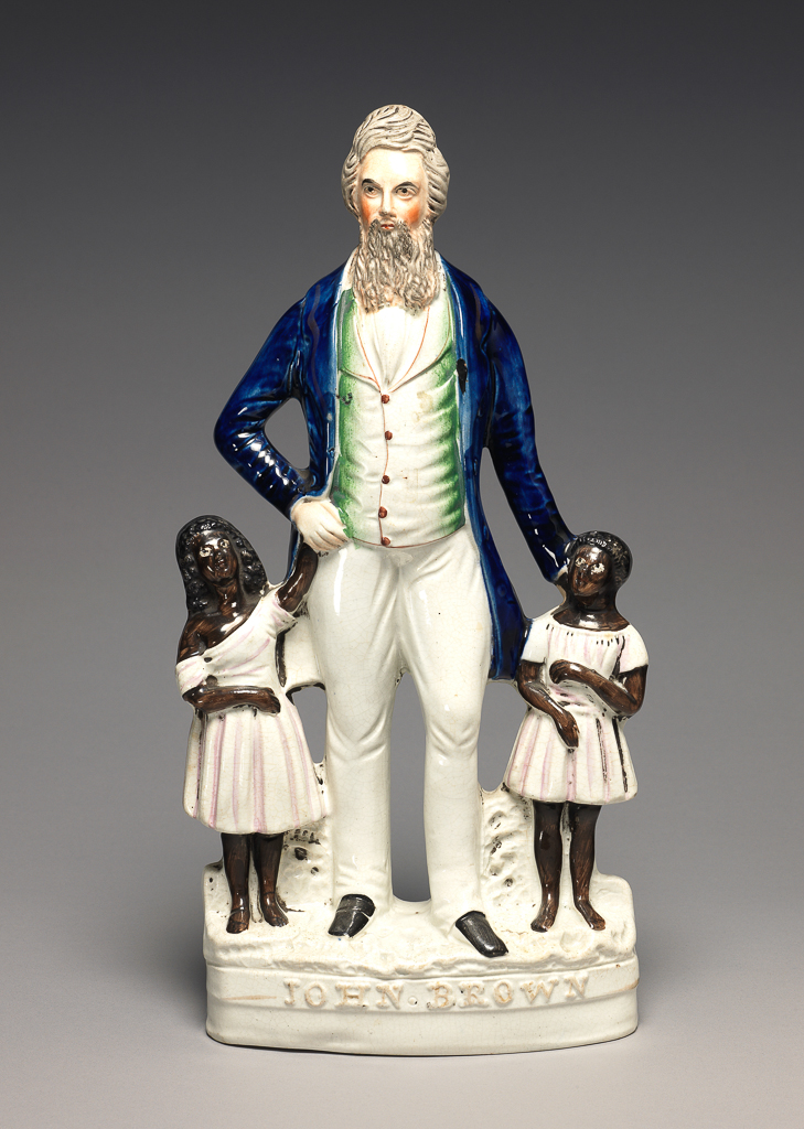 An image of Lead-glazed Earthenware / Figure Group. John Brown with Slave Boy and Girl. Unidentified factory. Flat-backed figure. White earthenware moulded in three parts and pearlware glazed. Painted underglaze in cobalt blue and with black, brown, grey, green, red, pink and flesh-pink enamels, and gilt. The underside is concave and glazed. Height, whole, 34.5 cm, width, whole, 16 cm, depth, whole, 8.5 cm. Circa 1859.