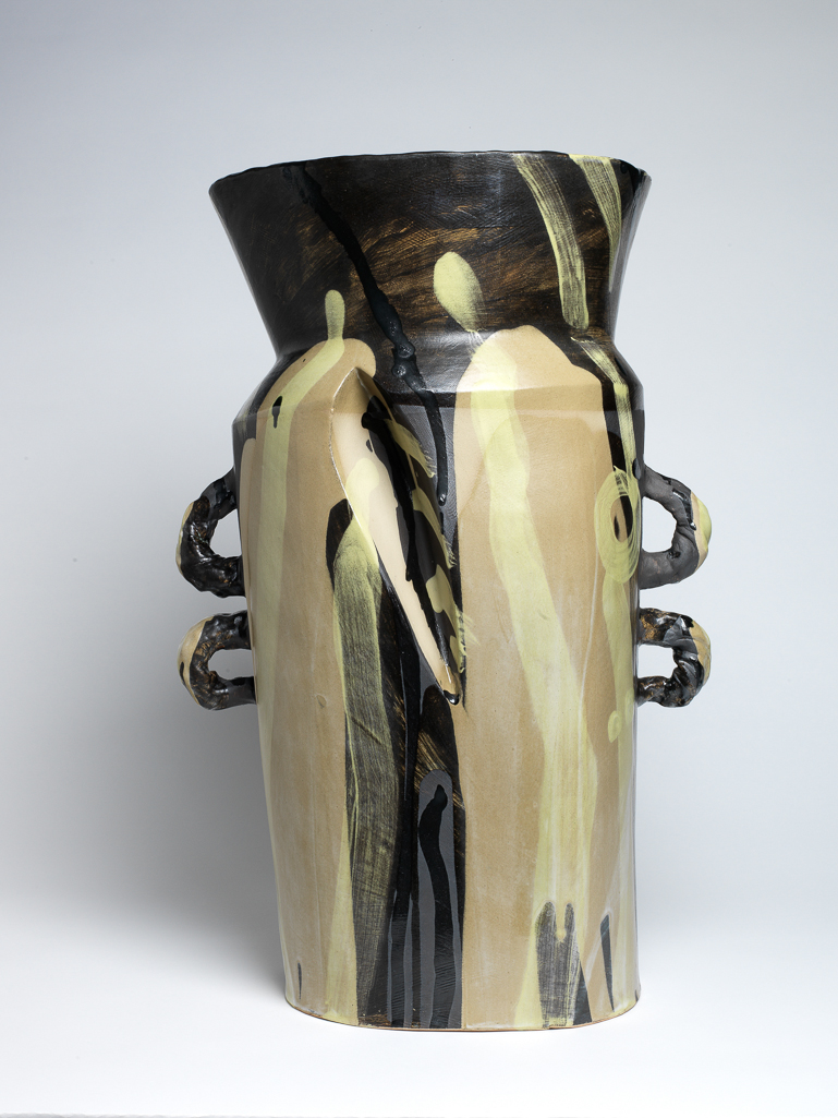 An image of Studio Ceramics. Dark Jar. Britton, Alison (British, b. 1948). Large slab built vessel, rising from an elliptical base into a churn-like form with a flared neck, two small loop handles on either side and a deep pleat folded into one face. The outside of the body is partially coated with smooth buff slip, with brown slip painted over the neck and reaching to the base in three arch-like shapes. The interior is roughly painted in black-brown and grey. Bold gestural marks in black-brown and  buff green are painted over the exterior and the inside of the neck. The underside is flat and unglazed. Earthenware, slab-built and painted. Height 57.5 mm, width 38 mm, depth 29.5 mm, 2015.