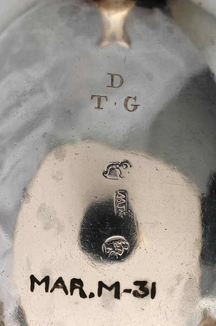 An image of Sauce Boat. West, Matthew, silversmith, probably, Ireland, Dublin. A deep oval with gadroon edged border; the sides undecorated; standing on three cast scroll legs with shell capitals and hoof feet; with leaf capped double scroll handle; the base scratch engraved with the initials 'D' over 'TG'. Silver, height, to top of handle, 10.8 cm, width, from lip to handle, 15.6 cm, weight, overall, 220 g, circa 1770-1786. Rococo.