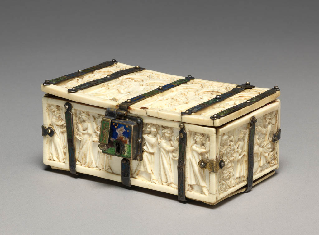 An image of Sculpture. Casket. Lid: Under six cusped arches with crocketted gables stand the figures of St Agnes, St Paul, St Peter, St John the Baptist, St Stephen, and St Catherine. Sides: Carved with scenes from the Martyrdom of St Catherine: her examination before Maxentius, the burning of the philosophers, the torture of the wheel, the beheading of the saint and her soul carried up to heaven. Mounts: Decorated alternately with panels of red, green and blue with pelican-like birds, salamanders and other fabulous beasts reserved in the metal. Lock-plate: Decorated with a hare in a field against a dark blue sky. Ivory, carved in relief,  with contemporary champlevé enamelled silver mounts. Height 4.4 cm, width 9.6 cm, depth 6.4 cm, circa 1370-1400. Production Place: Paris, France. Gothic. Medieval.