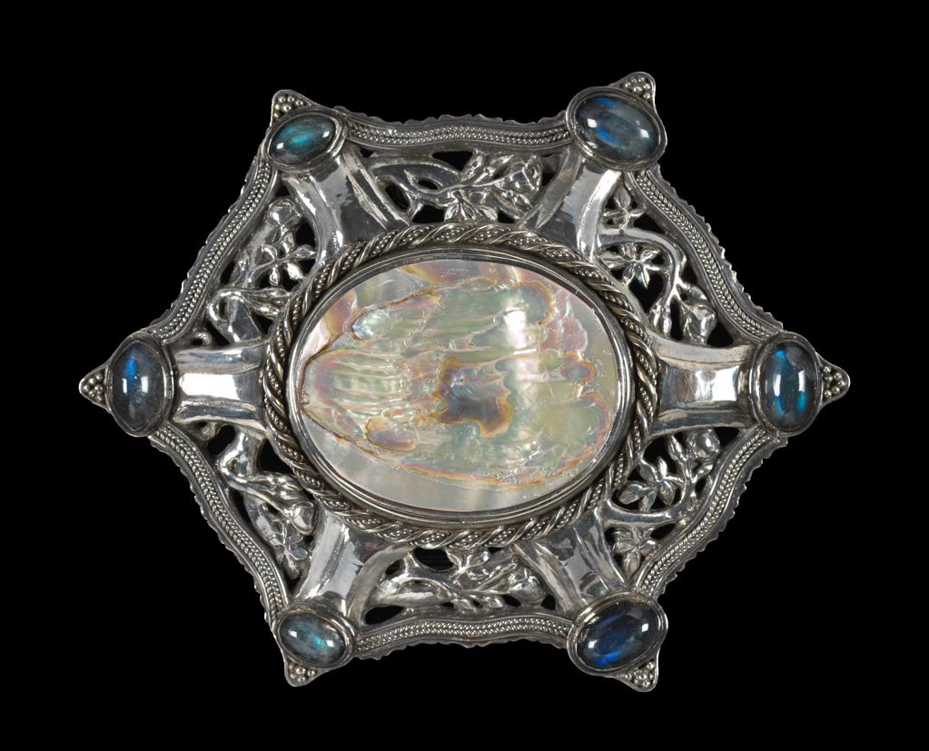 An image of Jewellery. Waist clasp. Cooper, John Paul (British, 1869-1933). Silver, with pierced rose and foliate design, with central oval of abalone shell and six oval cabochon cut labradorites. Height, whole, 10.5 cm, width, whole, 8.4 cm, 1902.