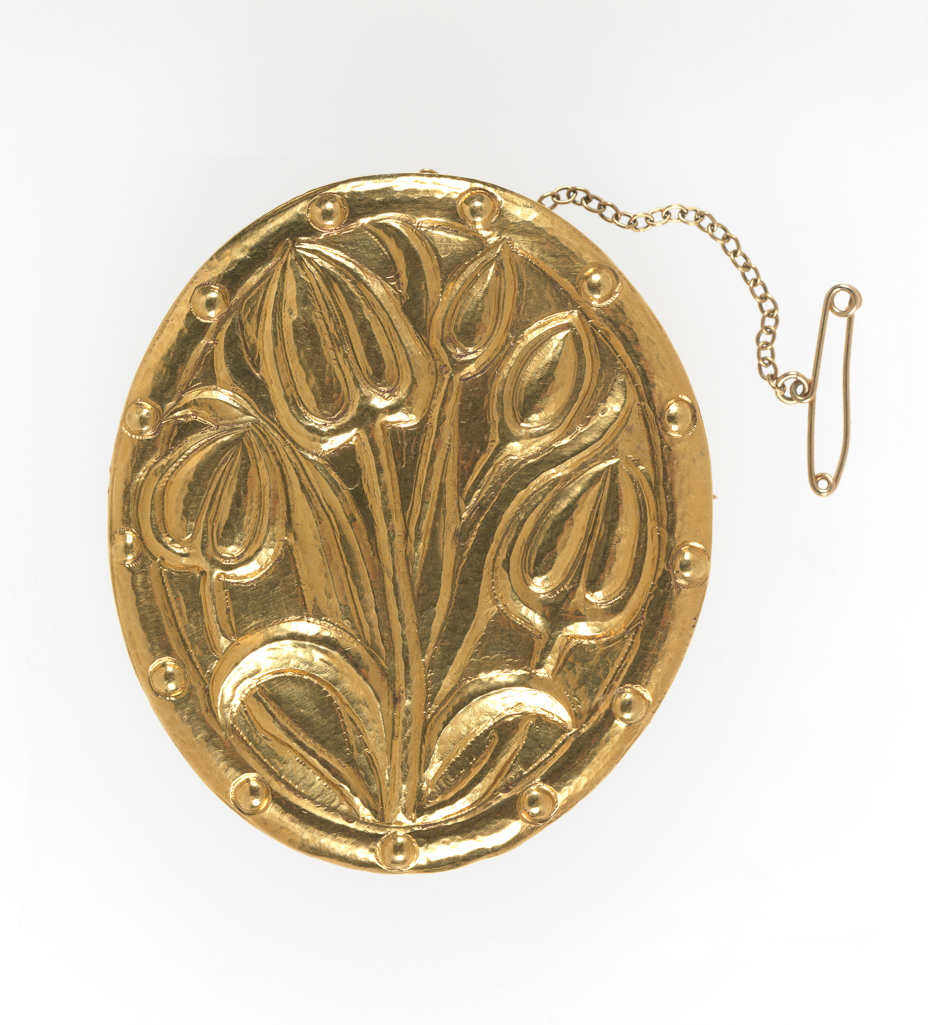An image of Jewellery/Brooch. Ashbee, Charles Robert, designer (British, 1863-1942). Hart, Henry, designer (British). Hart, David, silversmith (British). 22 carat gold, oval with embossed tulips and border of thirteen small bosses. In associated red leather case, initialled and dated in gold 'C.L.C./1906' on the top of the lid. (A). H.O. Hart's invoice for the brooch (B). Hart address card used as a gift card addressed to Mr Ward's mother in 1979 (C). Gold brooch, embossed, leather case. Designed 1906, made 1979. Arts and Crafts. 