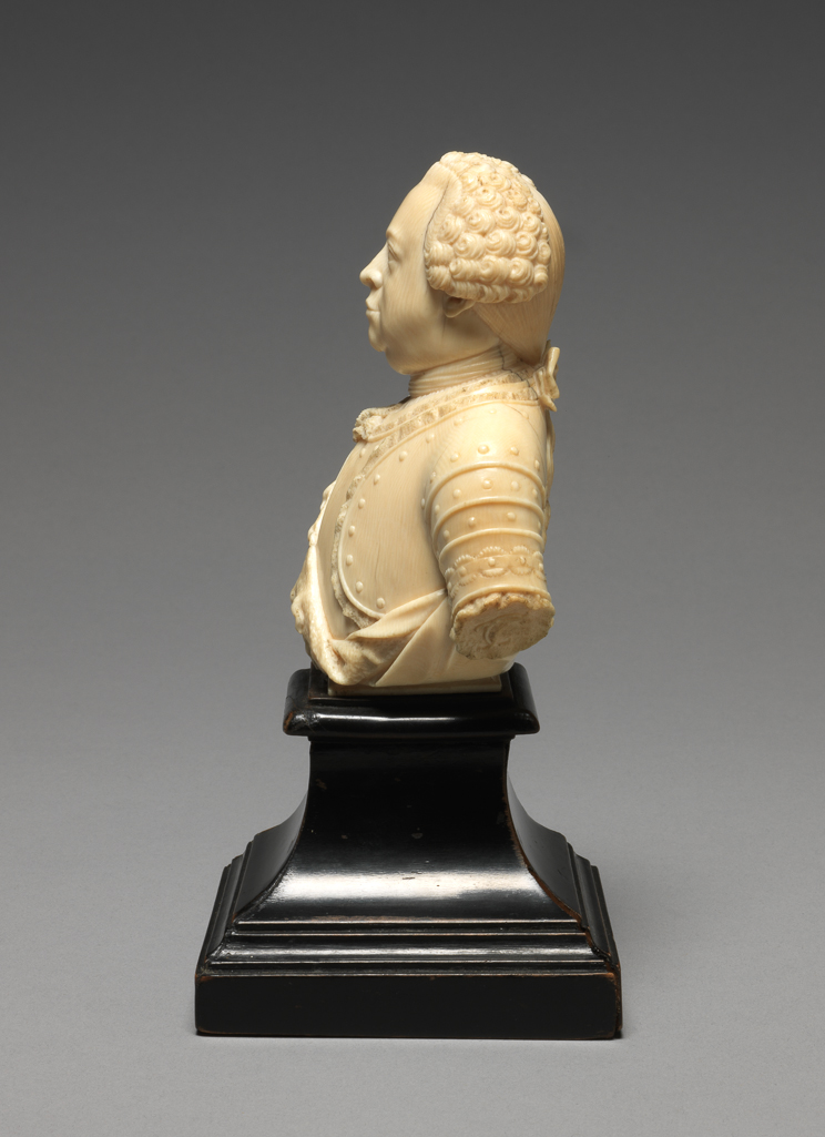 An image of Sculpture / Bust. Portrait Bust of Carl Theodor, Elector Palatine. Full-face, wearing periwig, cravat and armour. His monogram, CT, is carved in relief on the left arm. Ivory carved in the round, height, whole, 9.4 cm, width, whole, 7.5 cm, 1764. German.
