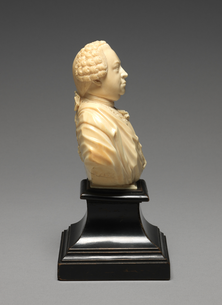 An image of Sculpture / Bust. Portrait Bust of Carl Theodor, Elector Palatine. Full-face, wearing periwig, cravat and armour. His monogram, CT, is carved in relief on the left arm. Ivory carved in the round, height, whole, 9.4 cm, width, whole, 7.5 cm, 1764. German.