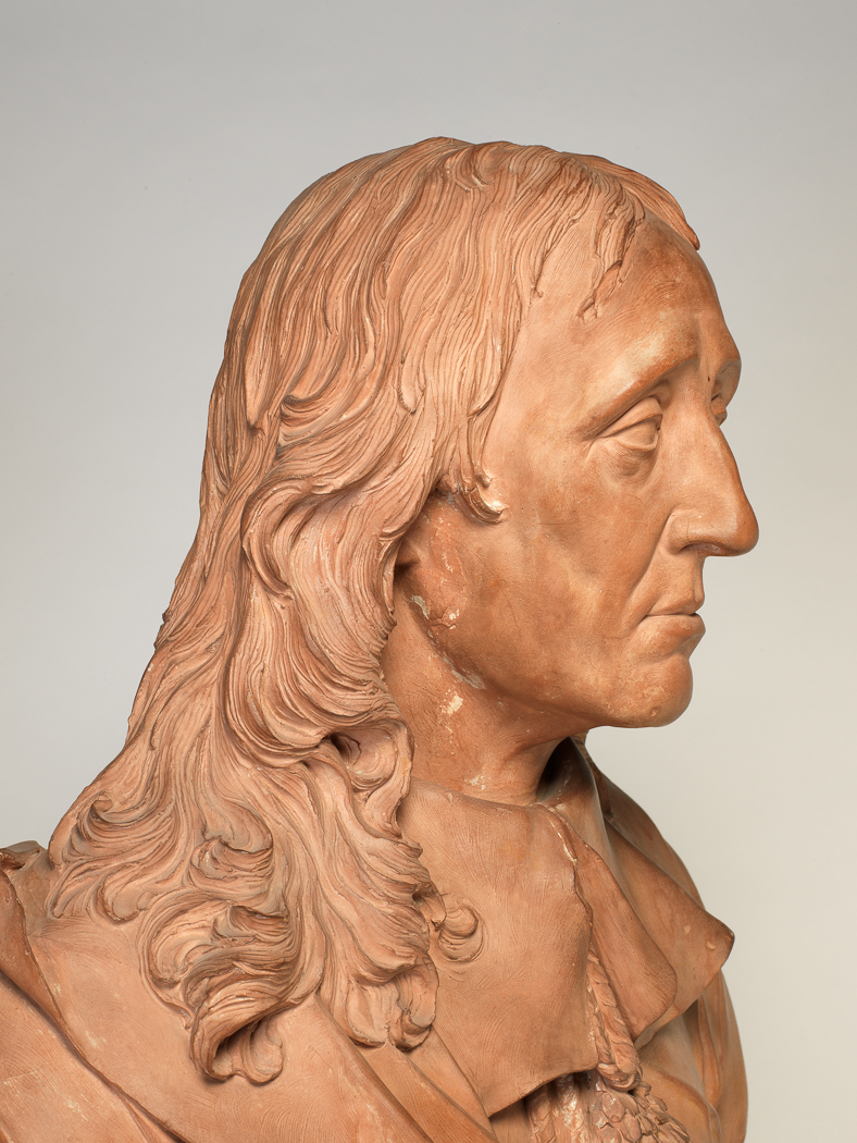 An image of Bust/Sculpture. John Milton (1608-1674). Rysbrack, John Michael (Briitsh, 1694-1770). The sitter is turned front, facing and looking slightly right. He is bare-headed, and his hair is falling long over the shoulders. He is clean-shaven. The sitter wears a doublet, with wide, falling-band collar, and drapery passing over the right shoulder, and under the left arm. The bust terminates in a low square base, inscribed on the front 'MILTON'. Terracotta, height 23 1/2 inches, dated 1738.