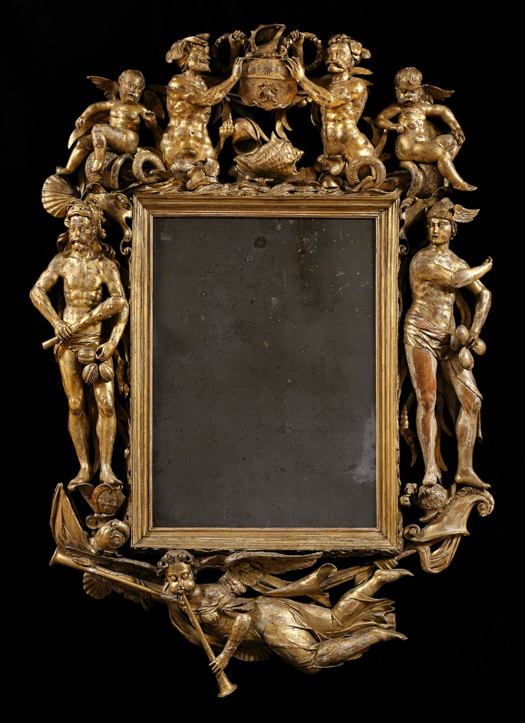 An image of Frame. Unknown Makers. Carved and gilded lime wood with central mirror plate, height 182 cm, width 129.5 cm, depth 13.5cm,  circa 1690s. English. Notes: The frame was commissioned by Admiral Edward Russell (1653-1727), the celebrated naval hero. Almost certainly made between 1693 and 1697 to honour Russell’s achievements and to celebrate his appointment as Admiral of the Fleet and First Lord of the Admiralty. The frame is decorated with symbols representing eternal glory. A personification of Fame with two trumpets flies beneath the mirror, which is flanked by two ancient  gods: Mercury representing trade, commerce and financial gain, and Hercules symbolising military strength and triumph. The carvers are unknown. They were probably Dutch or French Huguenots based at Deptford’s naval dockyard, more  used to carving elaborate ship prows and interiors than decorative pieces for a country estate.