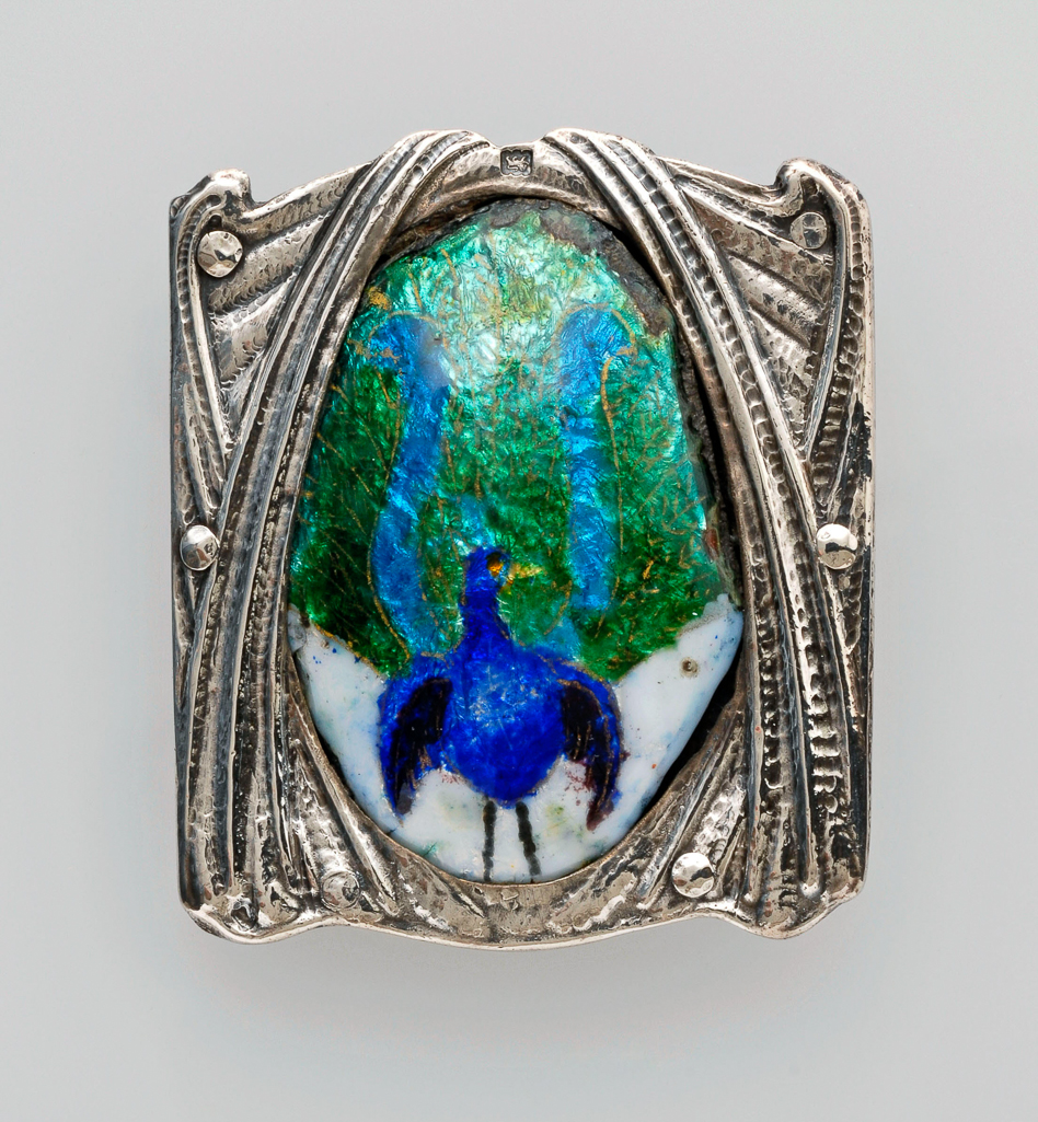 An image of Jewellery. Waist clasp. Ramsden and Carr. Ramsden, Omar (British, 1873-1939). Carr, Alwyn Charles Ellison (British, 1872-1940). Silver, chased and set with an oval plaque enamelled in blue, turquoise, green and white with a lyre bird. The silver back plate is inscribed 'RAMSDEN & CARR/MADE ME 1903'. Detached loop for the other end of the belt. Height, whole, 5.7 cm, width, whole, 5.0 cm, dated 1903. English. Acquisition: Grundy, J. Hull, Mrs.