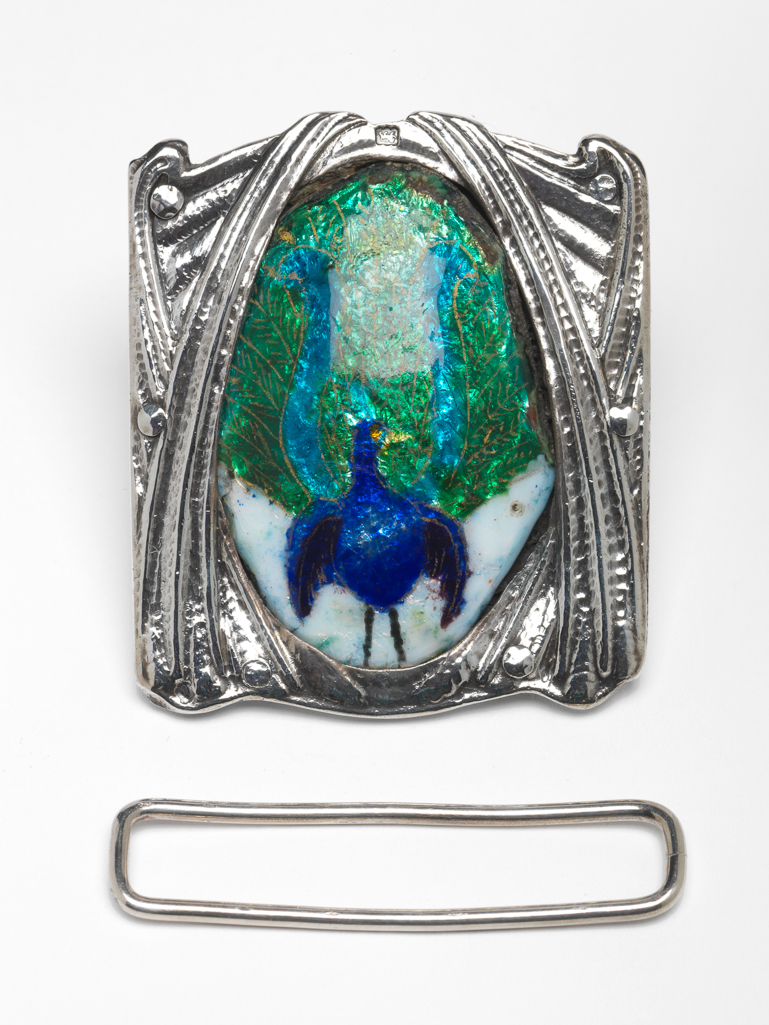 An image of Jewellery. Waist clasp. Ramsden and Carr. Ramsden, Omar (British, 1873-1939). Carr, Alwyn Charles Ellison (British, 1872-1940). Silver, chased and set with an oval plaque enamelled in blue, turquoise, green and white with a lyre bird. The silver back plate is inscribed 'RAMSDEN & CARR/MADE ME 1903'. Detached loop for the other end of the belt. Height, whole, 5.7 cm, width, whole, 5.0 cm, dated 1903. English. Acquisition: Grundy, J. Hull, Mrs.