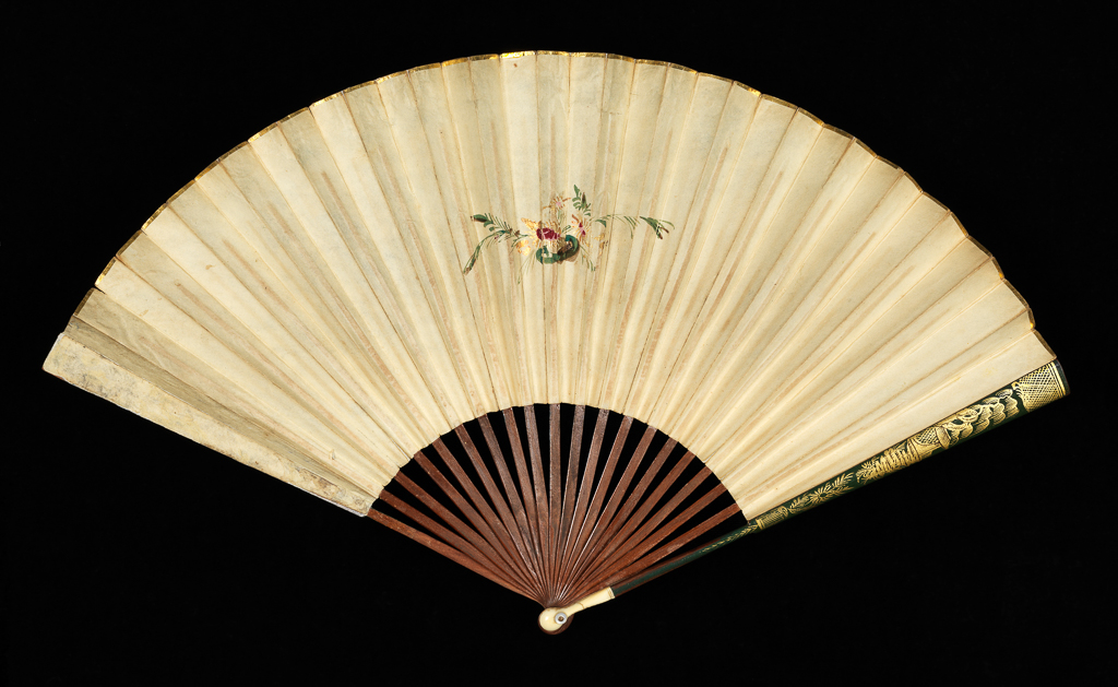 An image of Folding Fan. English, unknown maker. Front: In the middle a young mother kneels in profile, holding out her arms to a small boy standing in front of her. Landscape background with distant hills, a lake or river and buildings. Gilt scroll border on the left, upper and right sides. Reverse: A floral spray in red, pink, green and gold. Sticks and guards: Oriental style plants, a pavillion by a tree and criss-cross diaper. The green lacquer and design stops short of the head. Reverse plain wood. Double paper leaf stipple printed, painted in water-colours and gilt. Gold paper binding on the upper edge. Sticks and guards of wood, lacquered green and gilt, the head of the latter strengthened with ivory (18+2). Rivet with mother-of-pearl washers. Length, guards, 25.6 cm, 1809. Notes: The source of the design was an engraving by M.N. Bate after Adam Buck (1759-1833) entitled 'Step by Step' in the series 'The Progress of Human Life'. It was printed by Ackerman, 101, Strand, London.